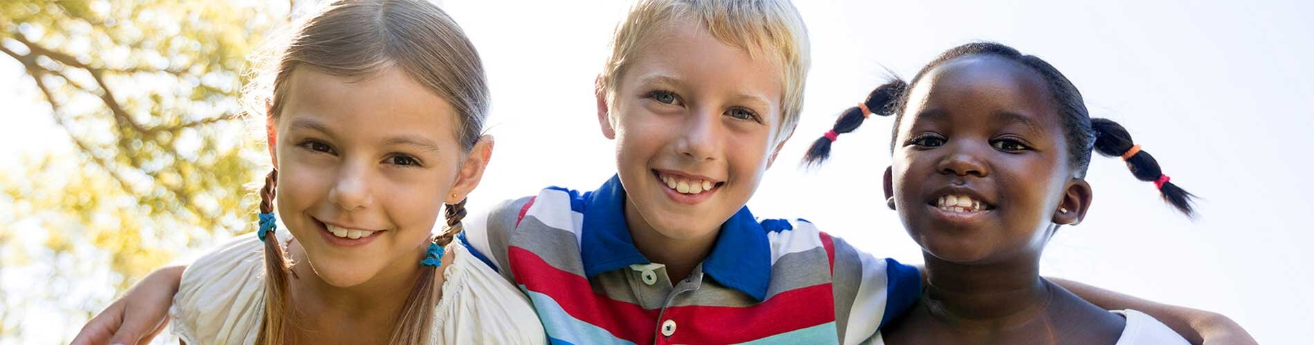 Three children embrace in a group hug.