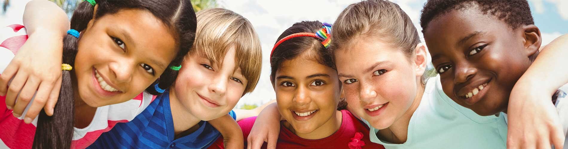 Five children embrace in a group hug.